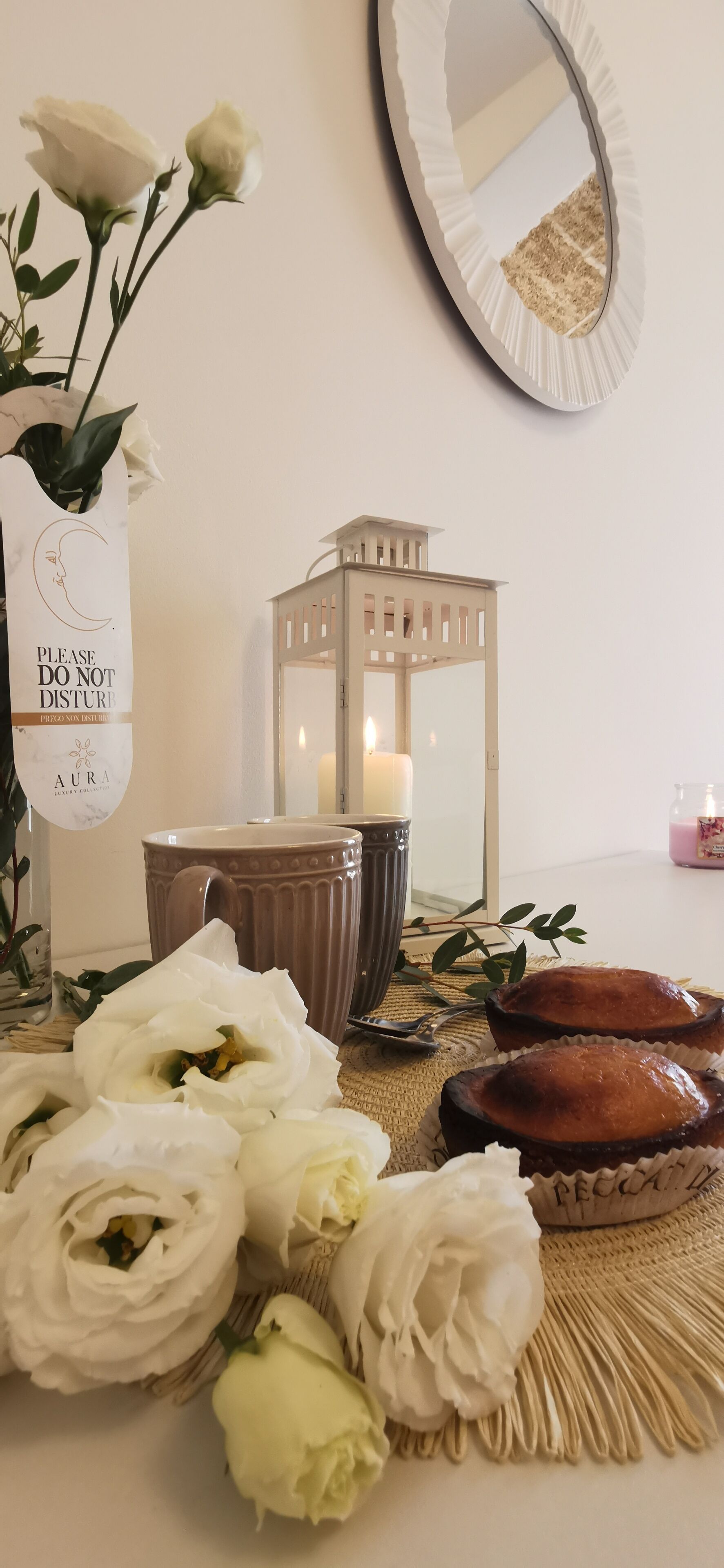 A table with white roses, a candle, a lantern, and a sign that says "PLEASE DO NOT DISTURB."