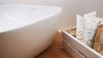 A bathroom with a white sink, chrome faucet, and a wooden tray holding toiletries.