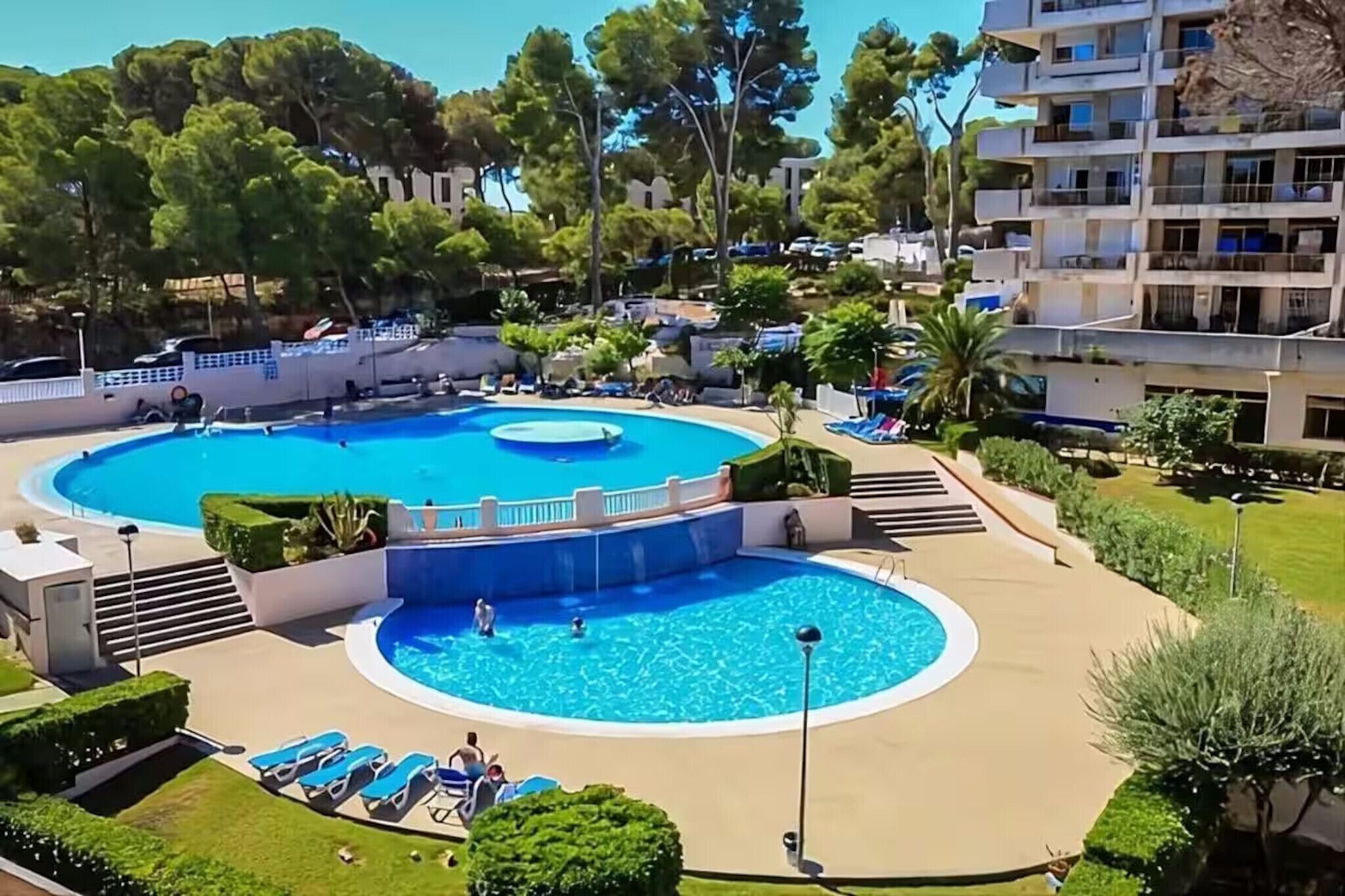 A large outdoor swimming pool with multiple levels and a surrounding deck area.