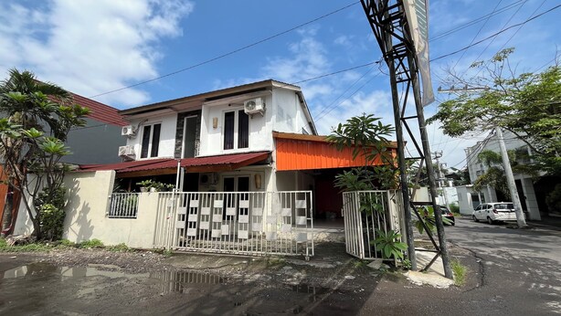 A two-story house with a red roof, a white fence, and a parked car in the background. - Spot on Homestay Griya Sunarti (Depok)