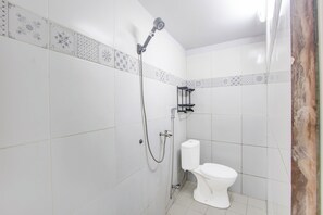 Un baño con azulejos blancos, una ducha y un inodoro.