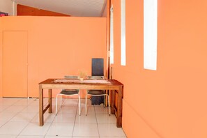Ein Zimmer mit einem Holztisch, zwei Stühlen, einem kleinen Topfpflanzen und einer weißen Tür.