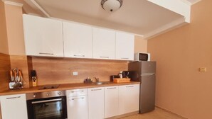 Eine moderne Küche mit weißen Schränken, einem Edelstahl-Kühlschrank und einem eingebauten Backofen.