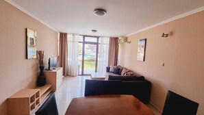 Ein modernes Hotelzimmer mit einem großen Bett, einer Couch, einem Fernseher und einem Esstisch.