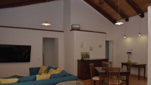 A living room with a blue sofa, wooden dining table, chairs, and pendant lights. - Luxurious retreat for your well-being (Valle dell'Angelo)