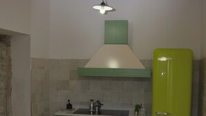 A kitchen with a wooden ceiling, green cabinets, a green refrigerator, and a dining table with chairs. - Luxurious retreat for your well-being (Valle dell'Angelo)