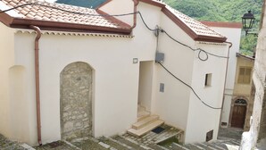 A narrow street with a building featuring a stone archway and a tiled roof. - Luxurious retreat for your well-being (Valle dell'Angelo)