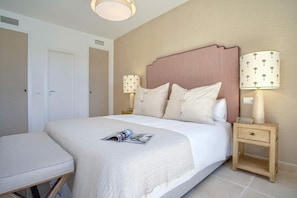 A neatly made bed with a magazine, a bedside lamp, and a nightstand.