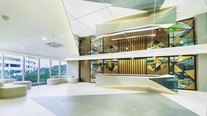 A modern interior with a spacious lobby, a mezzanine level, and large windows offering a view of the outdoors. - Grand Whiz Hotel Praxis Surabaya (Surabaya)