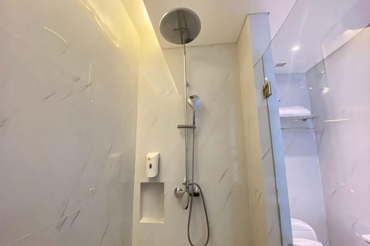 Un baño moderno con ducha, dispensador de jabón y perchero para toallas.