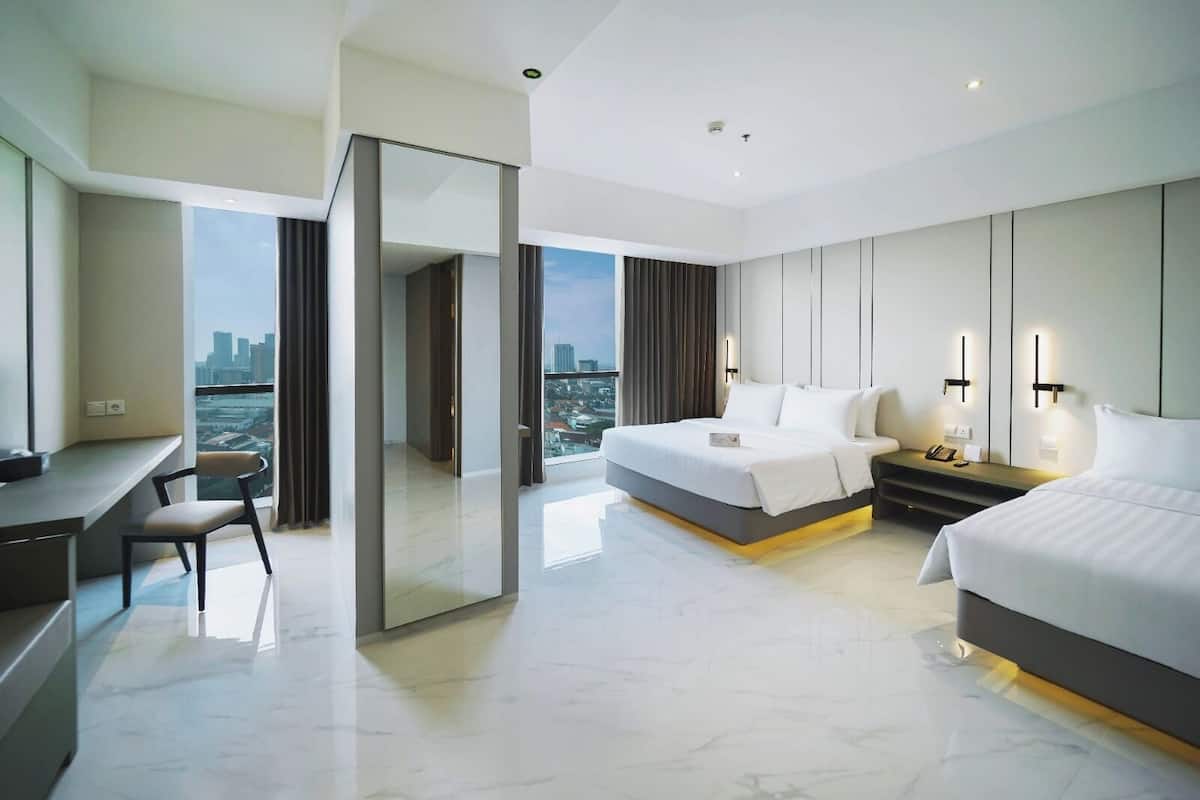Habitación de hotel moderna con una cama grande, un escritorio y una silla. Se ve una vista de la ciudad a través de la ventana.