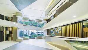 A modern interior with a spacious lobby, a mezzanine level, and a view of greenery outside. - Grand Whiz Hotel Praxis Surabaya (Surabaya)