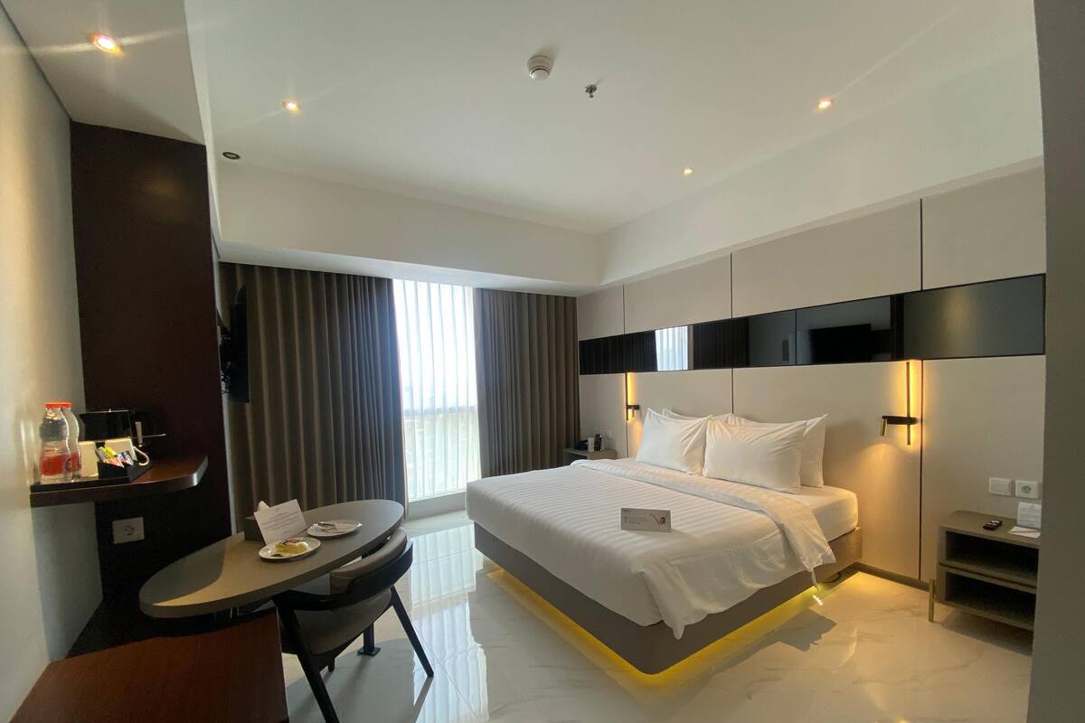 Una habitación de hotel moderna con una cama grande, un escritorio y una silla.