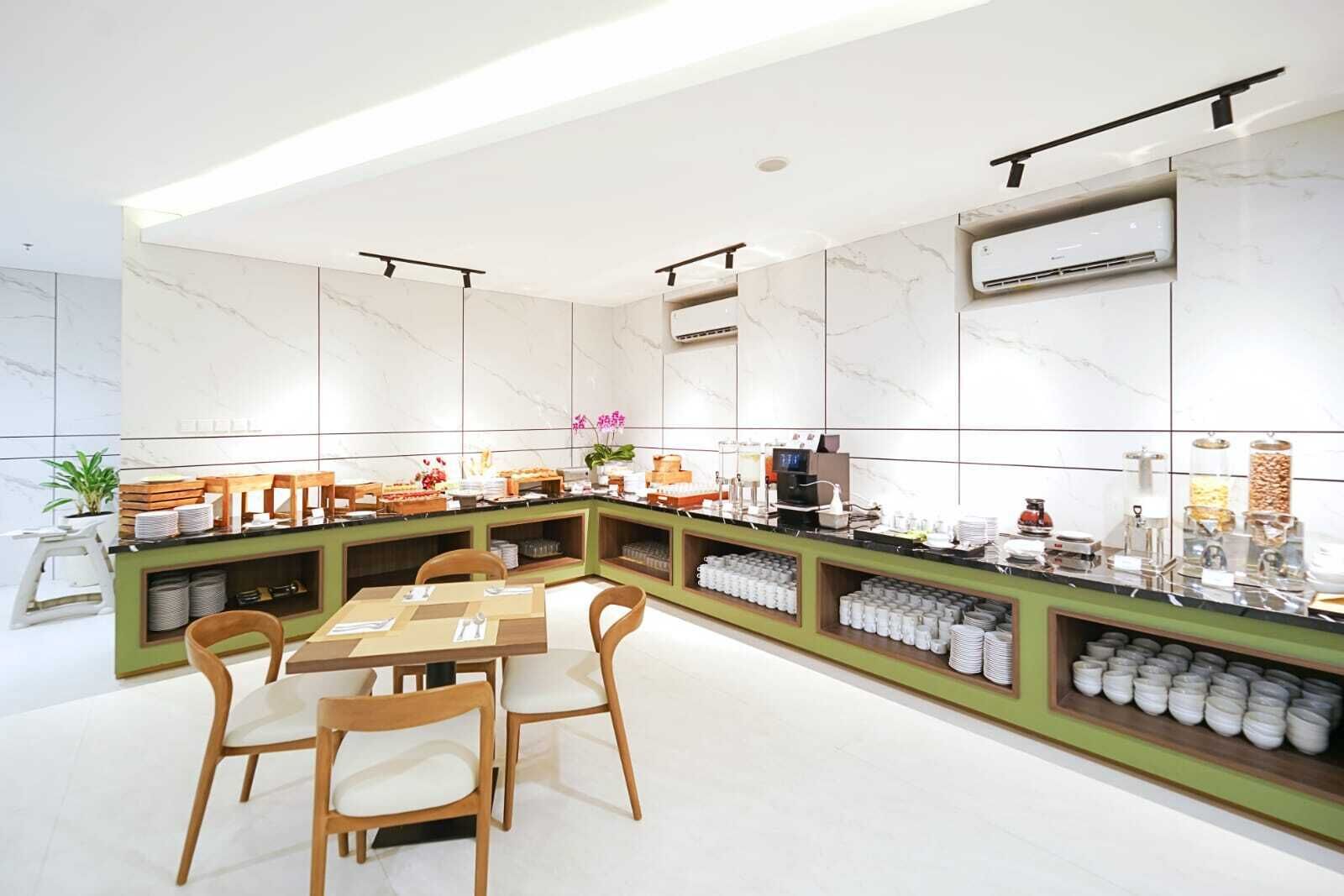 A modern breakfast bar with a green counter, white marble walls, and a seating area with wooden chairs.