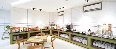 A modern breakfast bar with a green counter, white marble walls, and a seating area with wooden chairs.