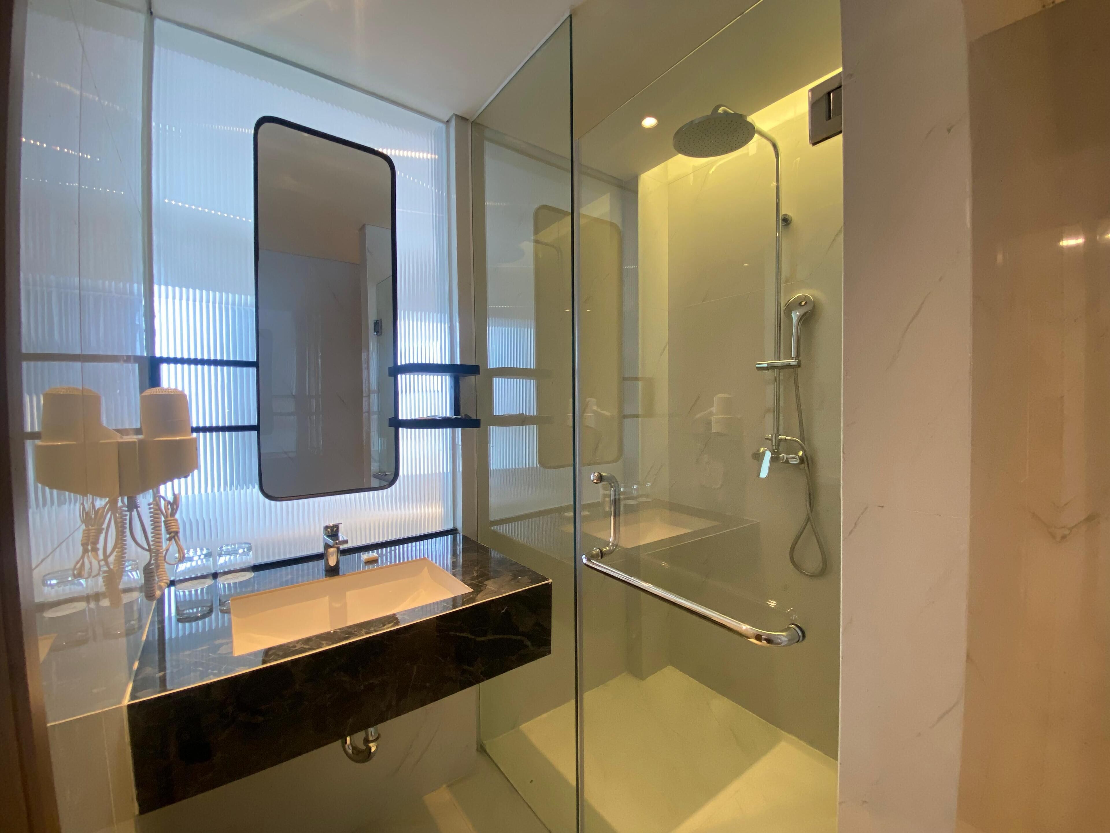 Une salle de bain moderne avec une douche à parois de verre, un meuble-lavabo avec un miroir et un évier.