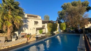 A poolside view of a building with a pool, outdoor seating, and surrounding greenery. - NEW! VILLA LORANA Between sea and vineyards (SAINT CYR)