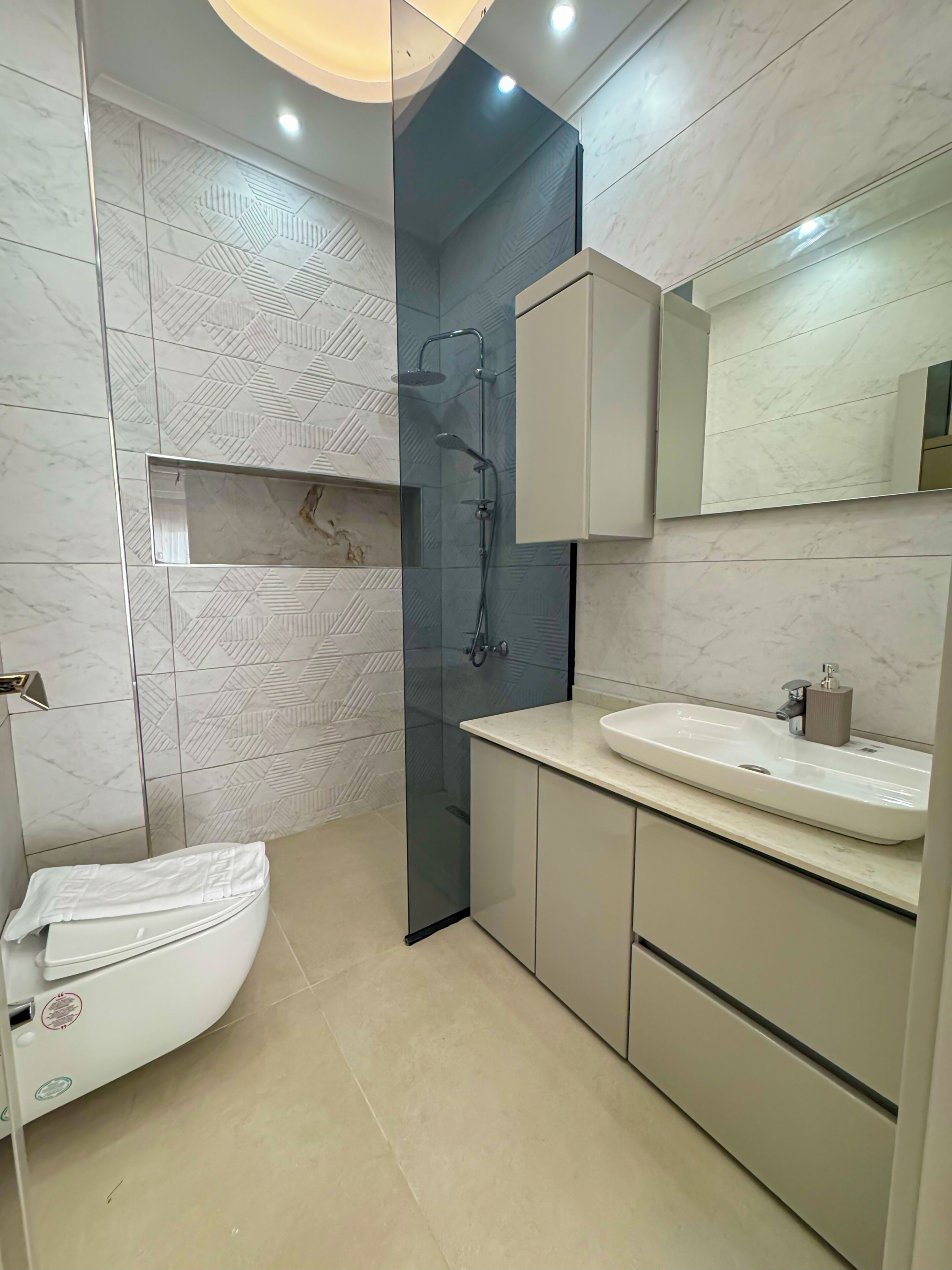 Une salle de bain moderne équipée de toilettes, d’une douche et d’un lavabo.