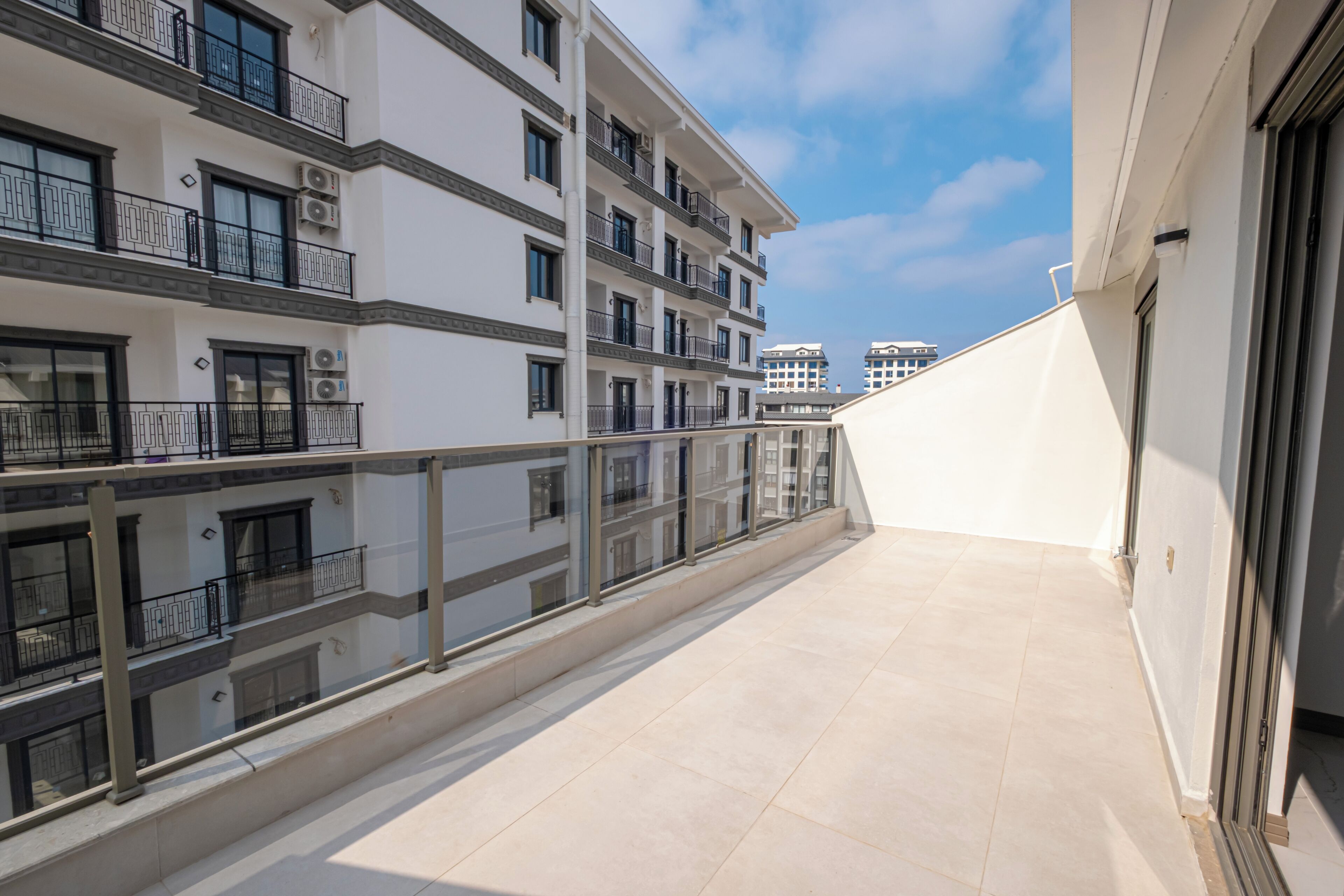 A multi-story residential building with balconies, large windows, and a tiled floor.