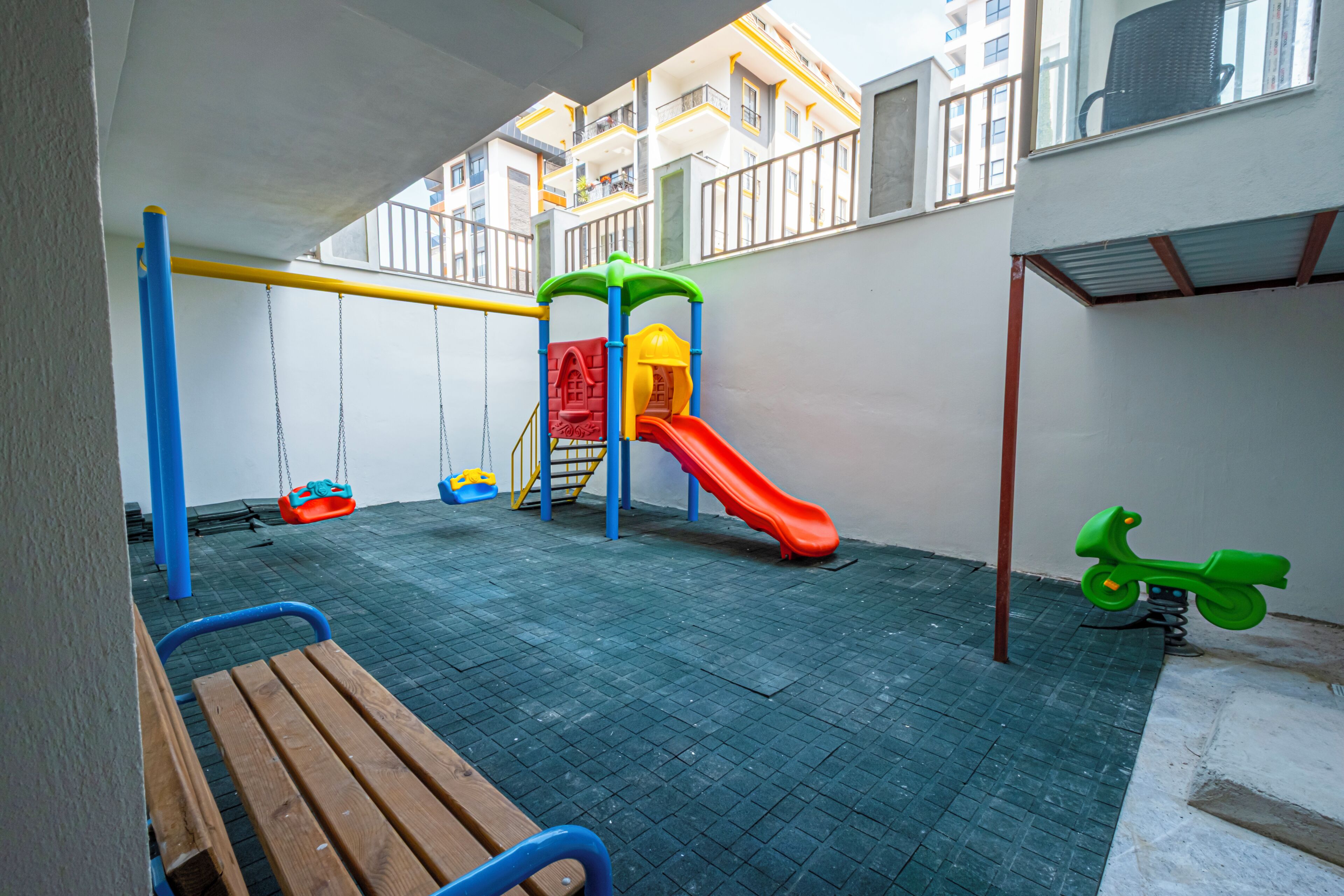 A children's play area with a slide, swings, and a bench.
