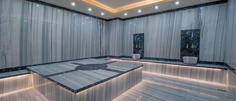 A modern bathroom with marble walls, a central island, and built-in lighting.