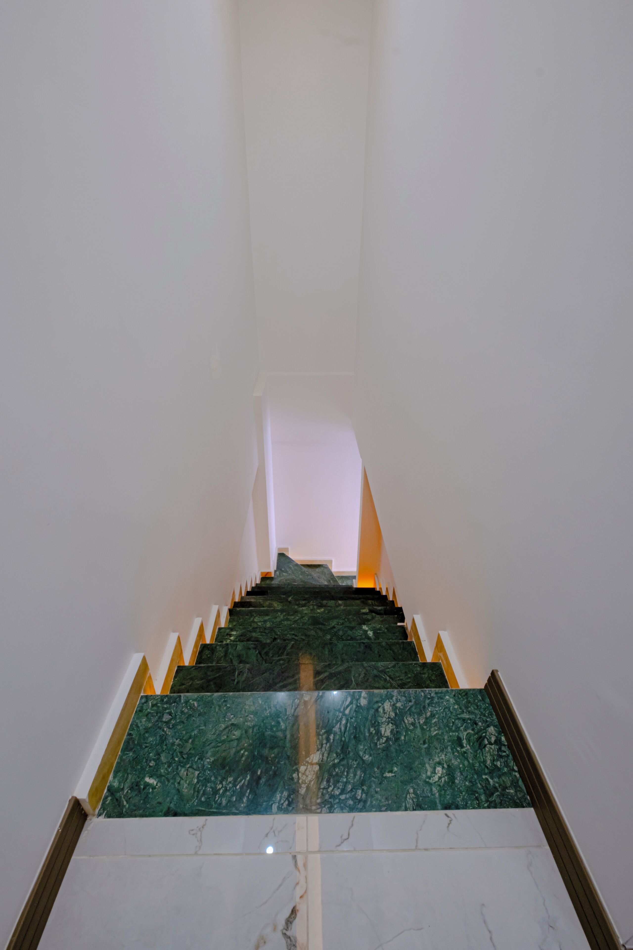 Eine Treppe mit grünen Marmorstufen und weißen Wänden.
