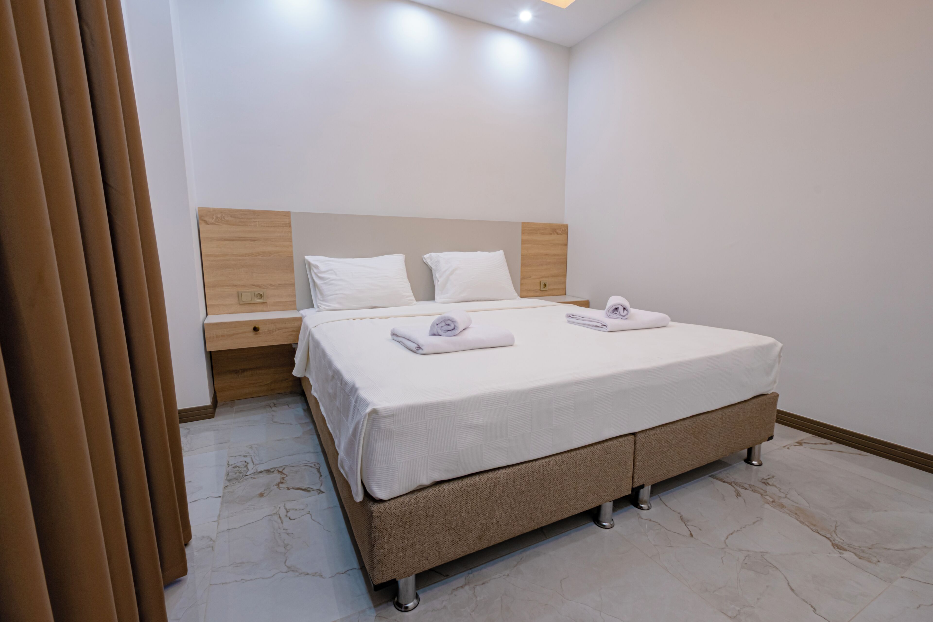 Een moderne hotelkamer met een groot bed, een houten hoofdbord en een nachtkastje.