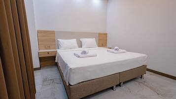 A modern hotel room with a large bed, wooden headboard, and a nightstand.