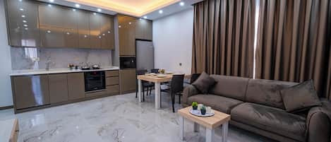 Una cocina moderna con electrodomésticos integrados, un comedor con mesa y sillas, y una sala de estar con sofá y una mesa de centro.