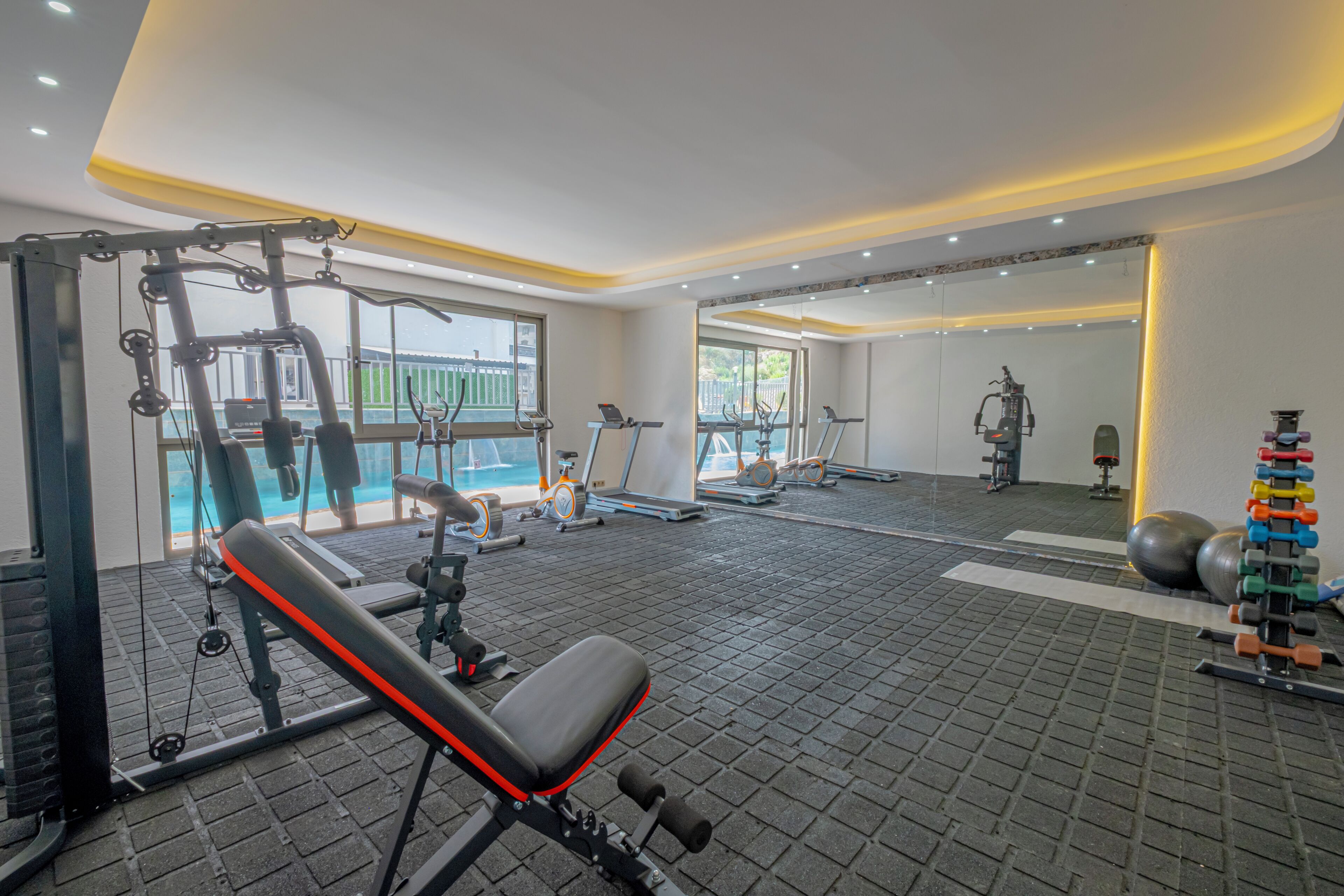 Un gimnasio con equipamiento de ejercicio, una banca y un espejo.