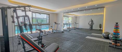 Un gimnasio con equipamiento de ejercicio, una banca y un espejo.