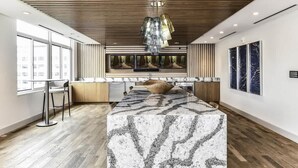 Une cuisine moderne dotée d’un îlot central, d’un plafond en bois et de grandes fenêtres.