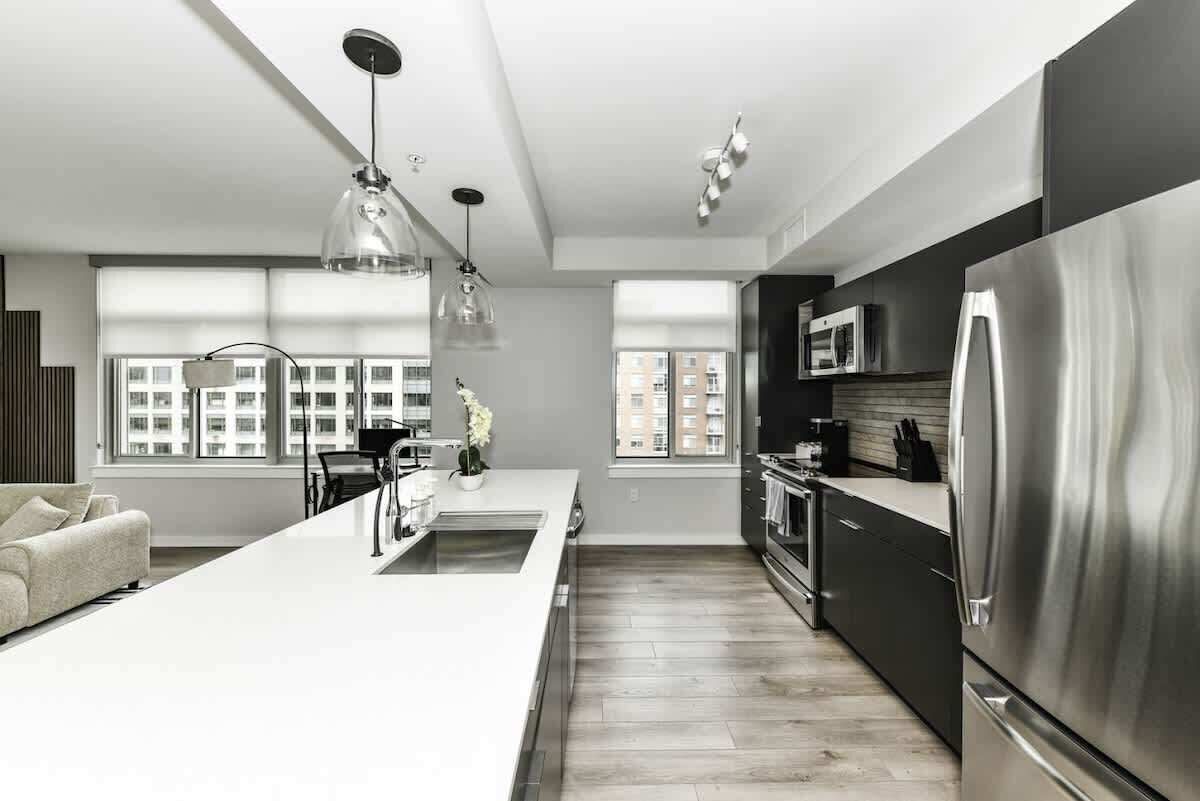 A modern kitchen with a central island, stainless steel appliances, and large windows providing natural light.
