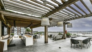An outdoor patio with a pergola, seating area, and a view of the river. - Modern 2BR Escape with Gym, Parking & Airport Views (Arlington)