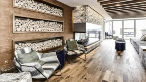 A modern living room with wooden flooring, a fireplace, and built-in shelves with logs. - Modern 2BR Escape with Gym, Parking & Airport Views (Arlington)