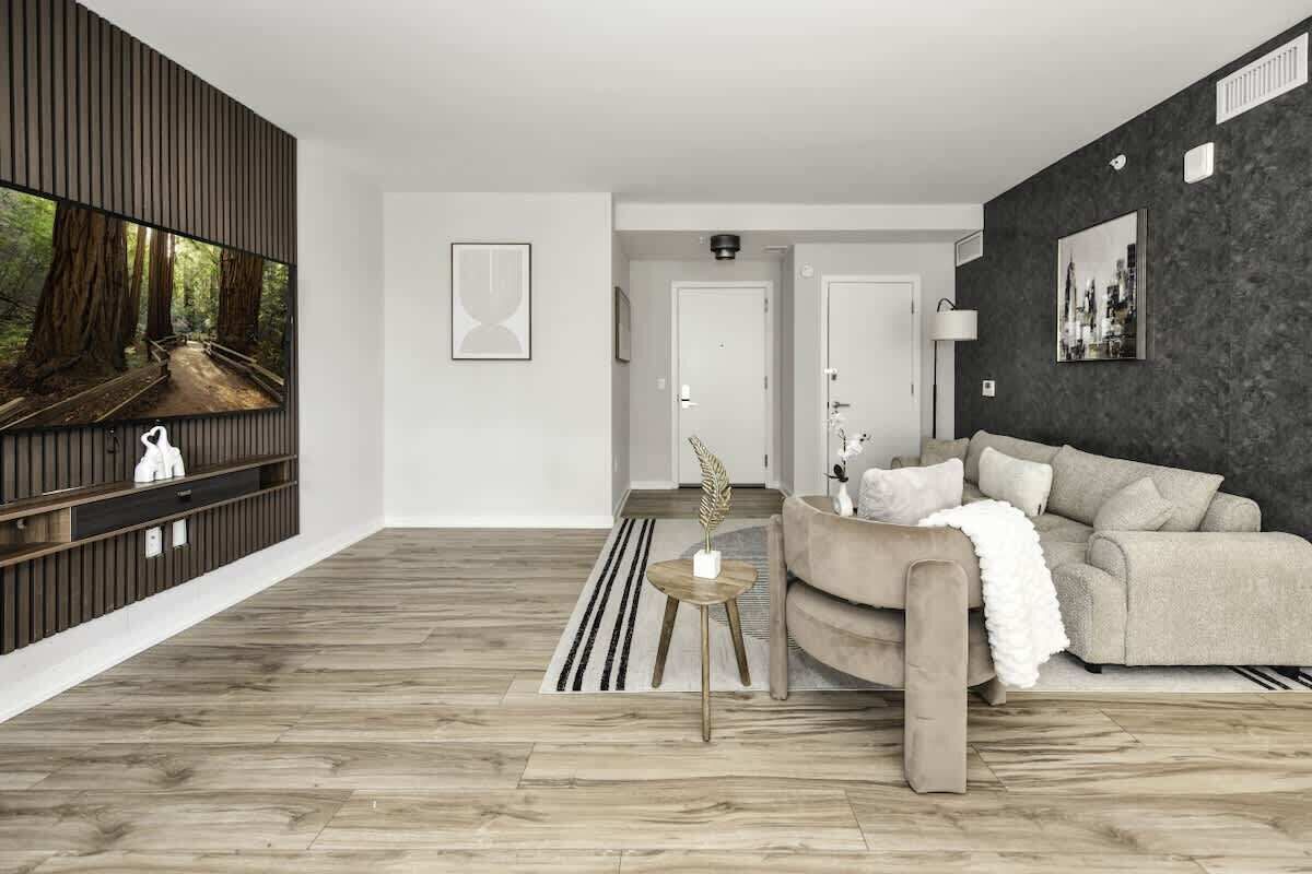 A modern living room with a large TV, a sofa, a coffee table, and a dark accent wall.