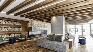 A modern living room with a fireplace, wooden beams, and a stone wall. - Stylish 2BR Stay with Gym, Parking & Rooftop Views (Arlington)