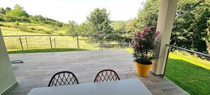 Une terrasse avec une table et des chaises, un pot de fleurs et une vue sur un paysage verdoyant.