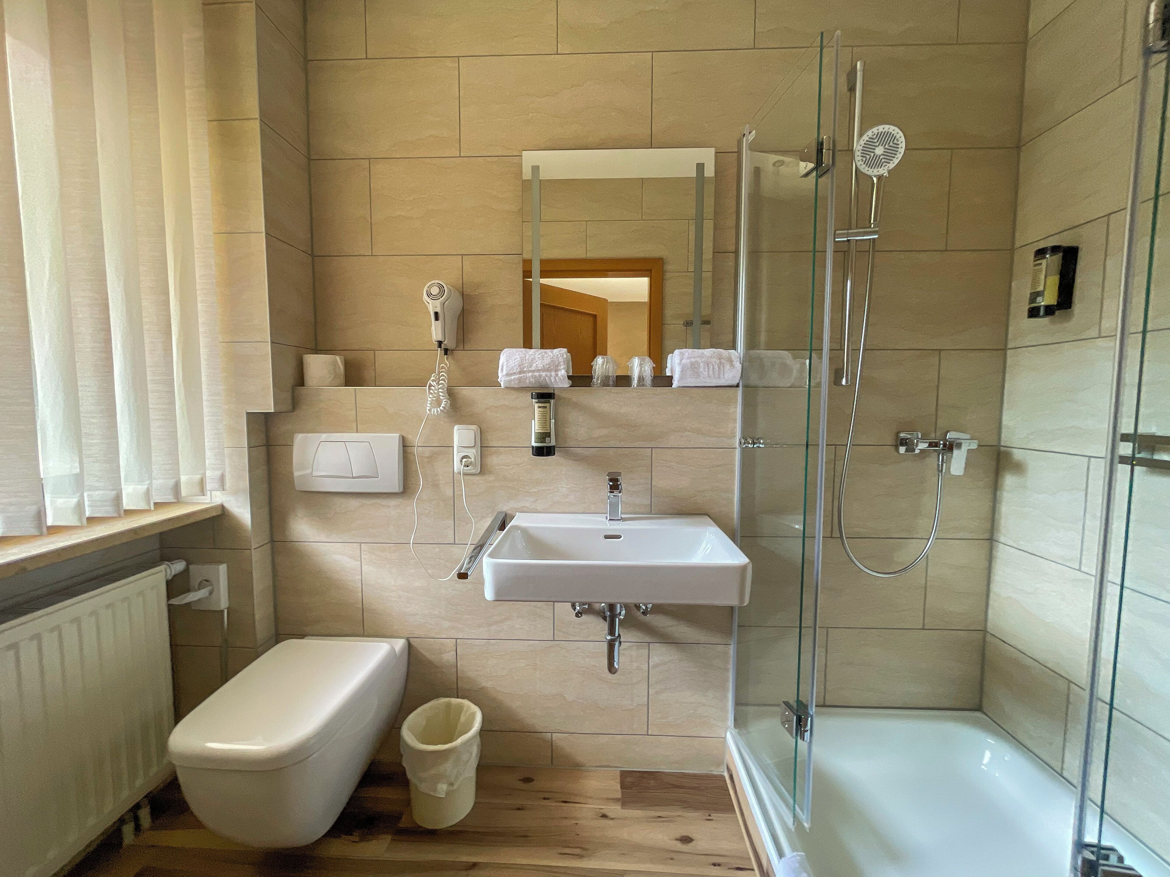 Ein modernes Badezimmer mit Toilette, Waschbecken und einer Duschkabine.