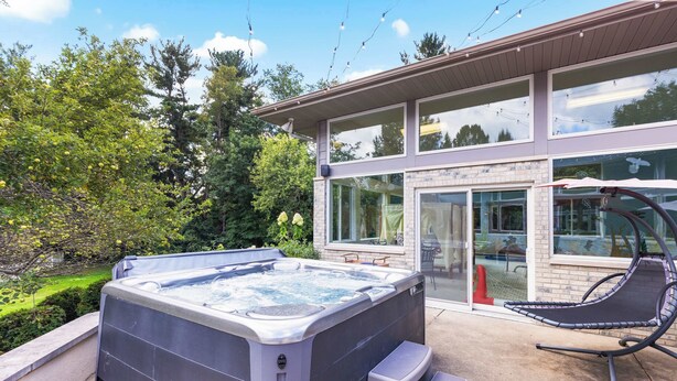 A modern house with a hot tub and a hammock chair on the patio. - Wembley Place Estate/Indoor Pool/Hot Tub/Game Room (Rockford)