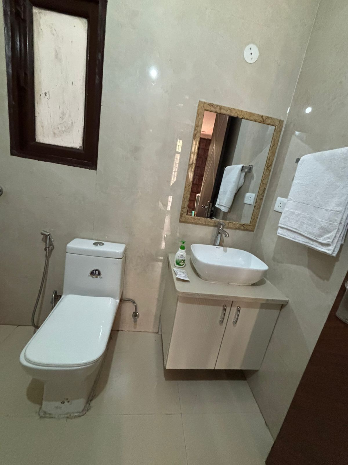 A bathroom with a toilet, sink, and mirror.
