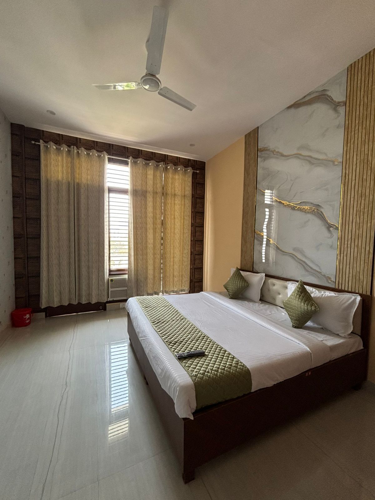 A spacious bedroom with a large bed, a ceiling fan, and a marble accent wall.