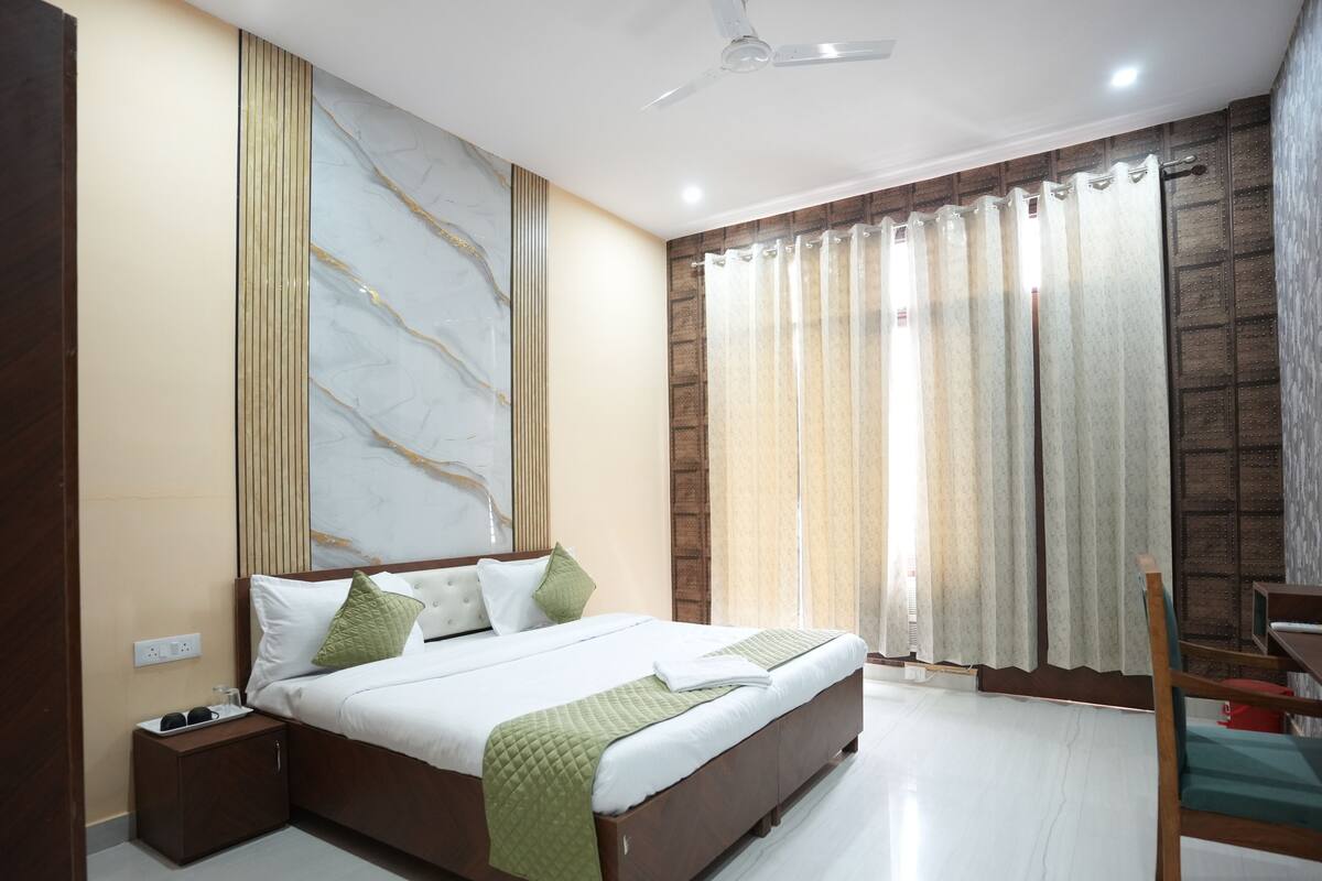 A modern bedroom with a large bed, a nightstand, a chair, and a ceiling fan.