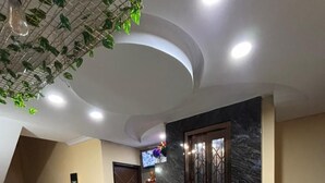 A modern living room with a staircase, a green sofa, a wooden coffee table, and a TV mounted on the wall. - Hotel Saina Stay Inn (Gurugram)