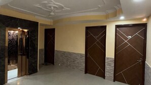 A spacious room with a polished marble floor, a decorative ceiling, and three doors with geometric patterns. - Hotel Saina Stay Inn (Gurugram)