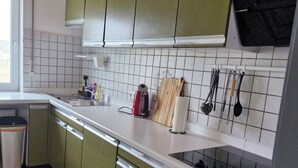 A kitchen with green cabinets, white countertops, and a tiled backsplash. - Spacious 4-room apartment for the whole family with an eat-in kitchen (Elsdorf)