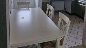 A kitchen with a white table and chairs, a microwave, and a view of the outdoors. - Spacious 4-room apartment for the whole family with an eat-in kitchen (Elsdorf)