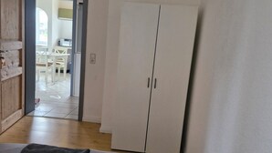 A room with a bed, a wardrobe, and a view of a dining area through an open door. - Spacious 4-room apartment for the whole family with an eat-in kitchen (Elsdorf)