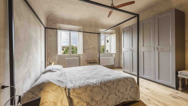 Un dormitori amb un llit amb cortines, un ventilador de sostre i vistes cap a l'exterior.