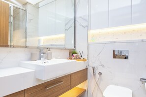 A modern bathroom with a white sink, wooden cabinet, and a glass shower enclosure.